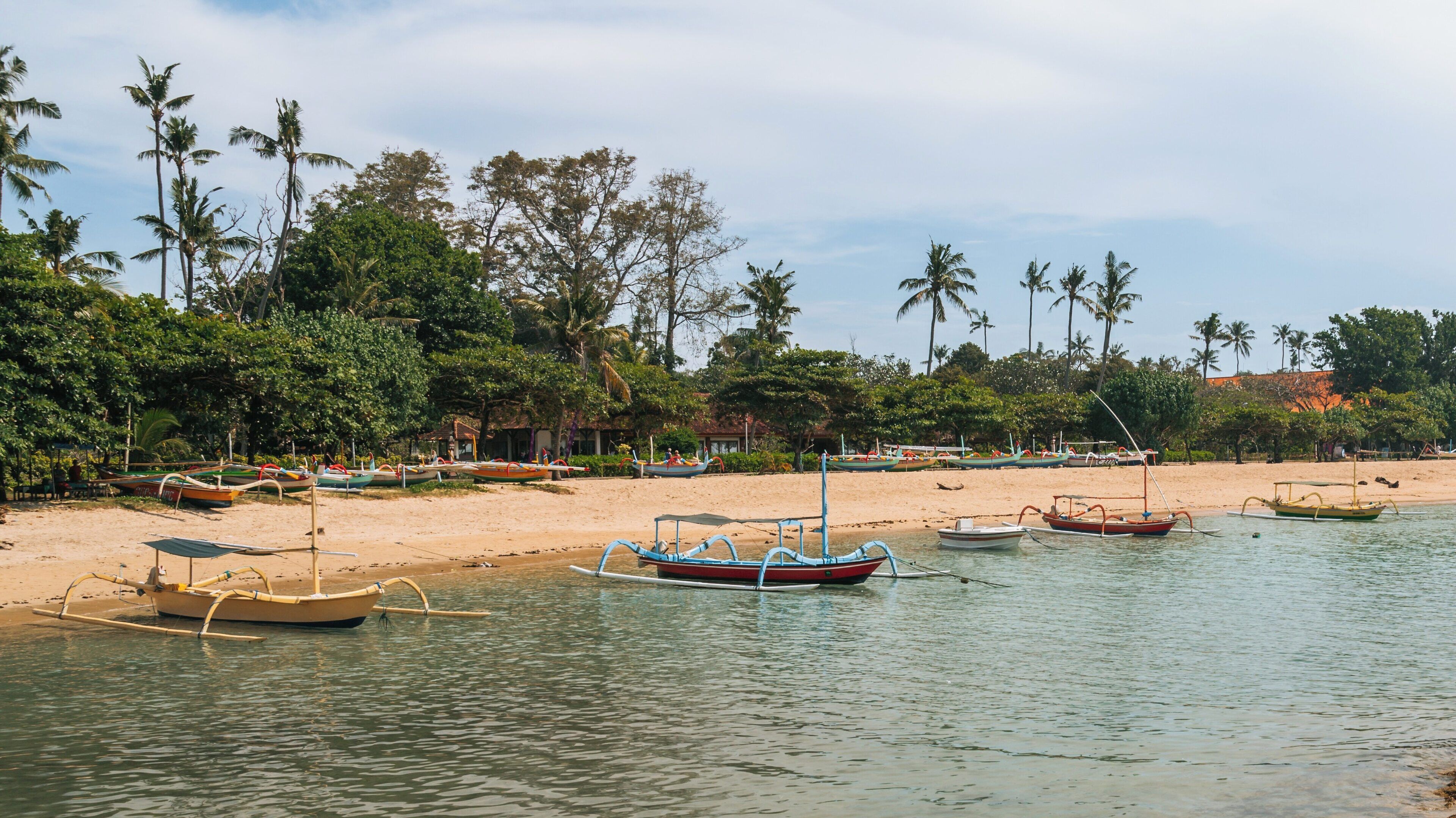 Calm waters and traditional fishing boats at Segara Beach in Kuta, Bali during a sunny day