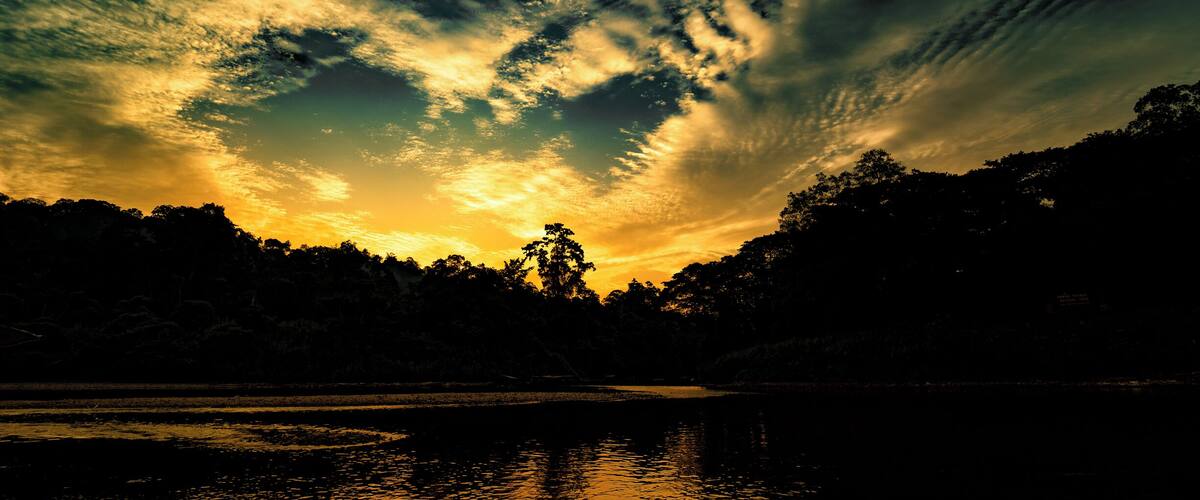 A sunset over a lake with a forested shoreline.
