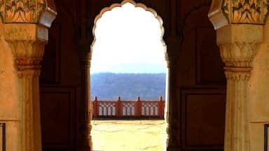 Uma porta ornamentada com esculturas detalhadas e vista para uma paisagem montanhosa ao fundo.