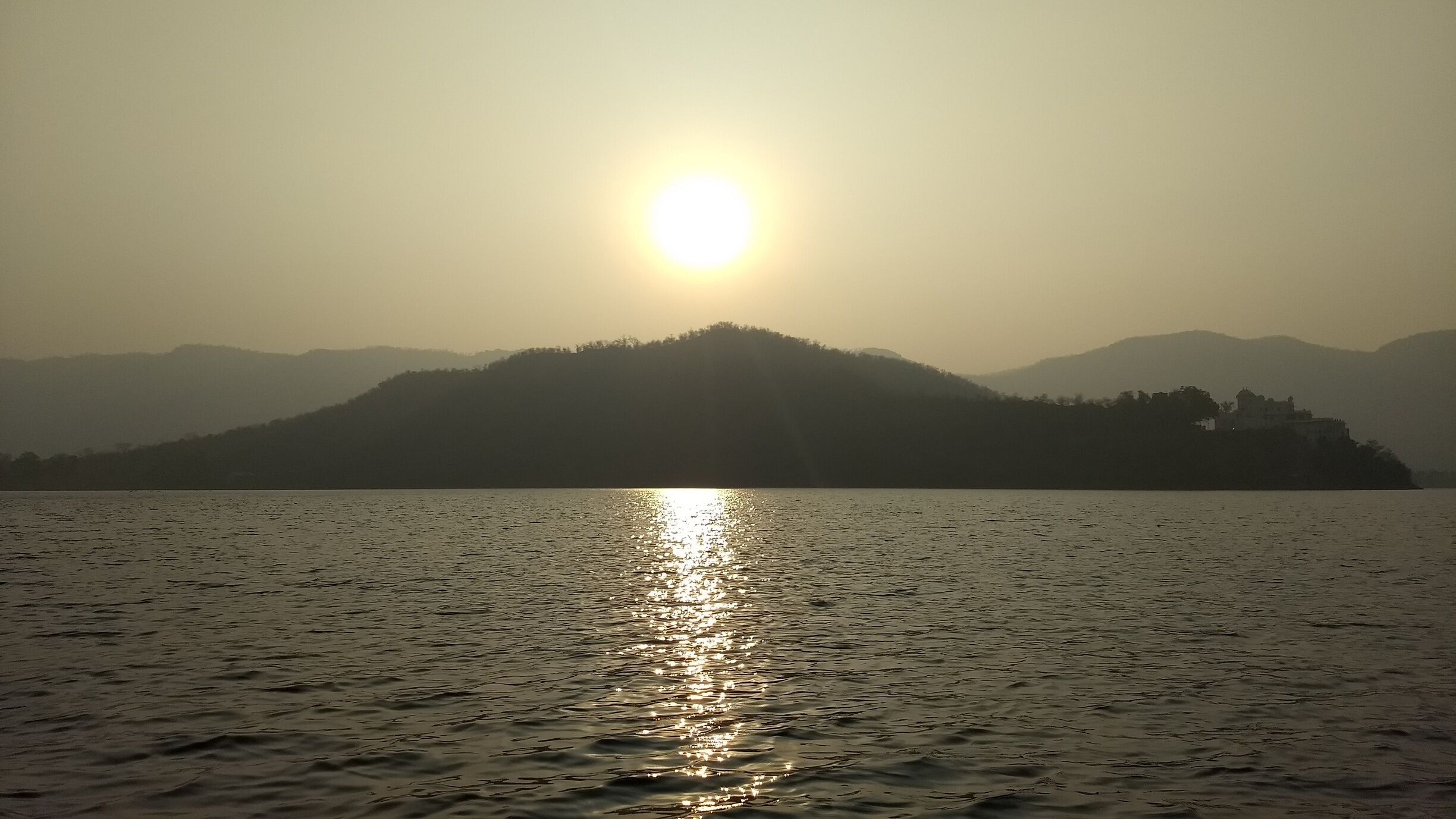 A sunset over a calm lake with a mountain in the background.