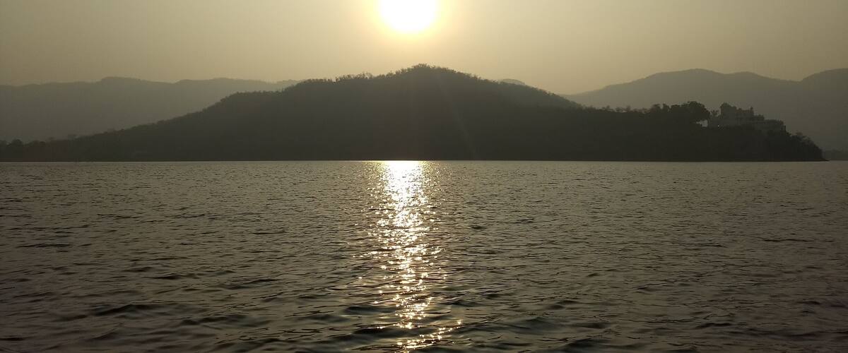 A sunset over a calm lake with a mountain in the background.