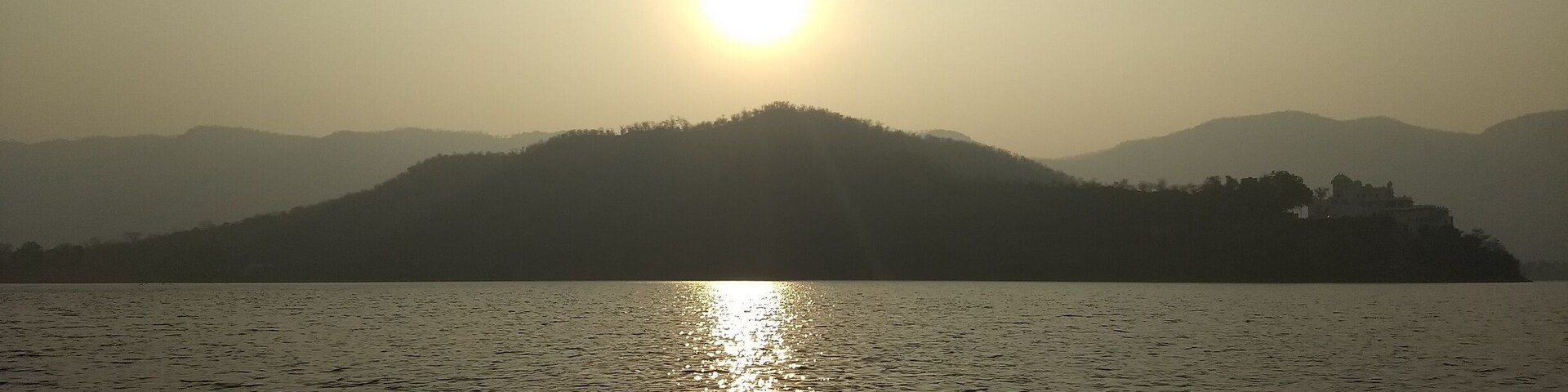 A sunset over a calm lake with a mountain in the background.