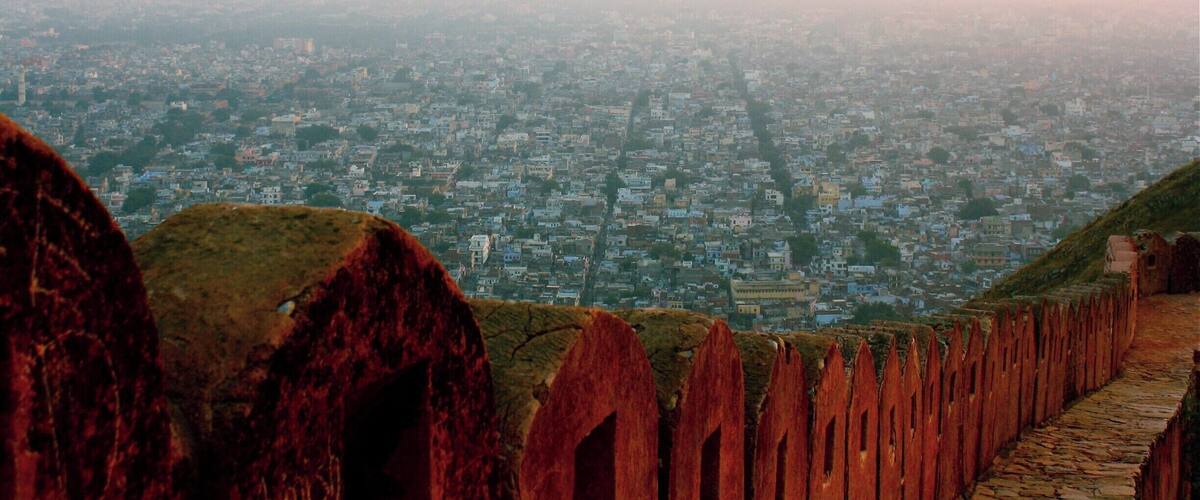 A cityscape with a prominent red fort structure in the foreground.