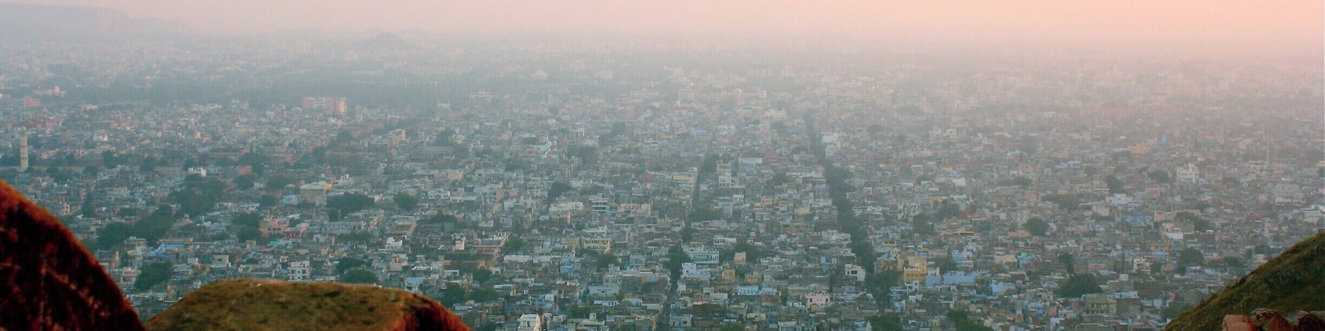 A cityscape with a prominent red fort structure in the foreground.