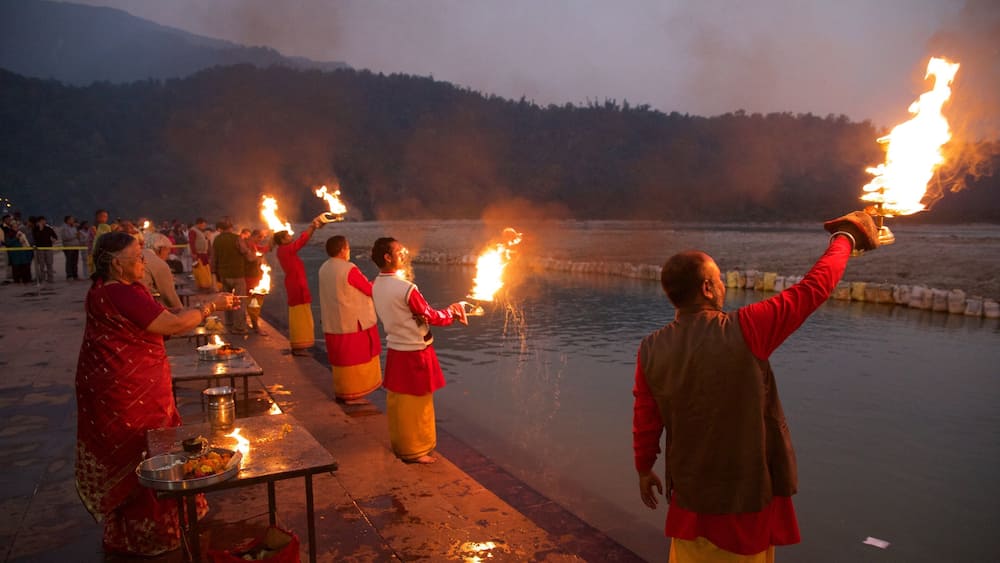 Triveni Ghat mettant en vedette coucher de soleil et aspects religieux aussi bien que petit groupe de personnes