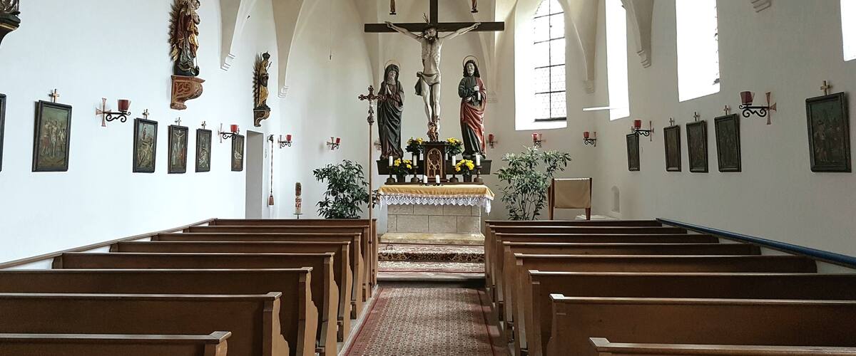 A church interior with wooden pews, a crucifix, and religious statues.