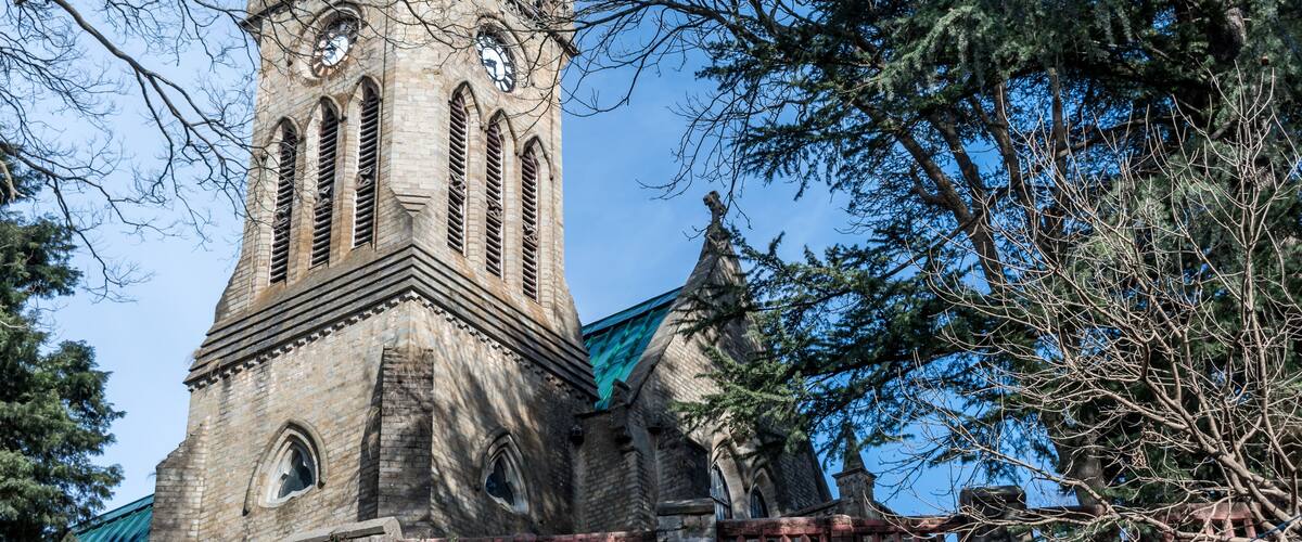 A historic church with a tall steeple, arched windows, and a clock.