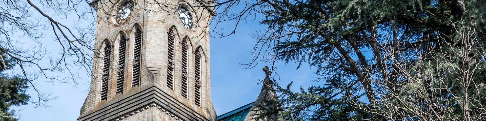 A historic church with a tall steeple, arched windows, and a clock.