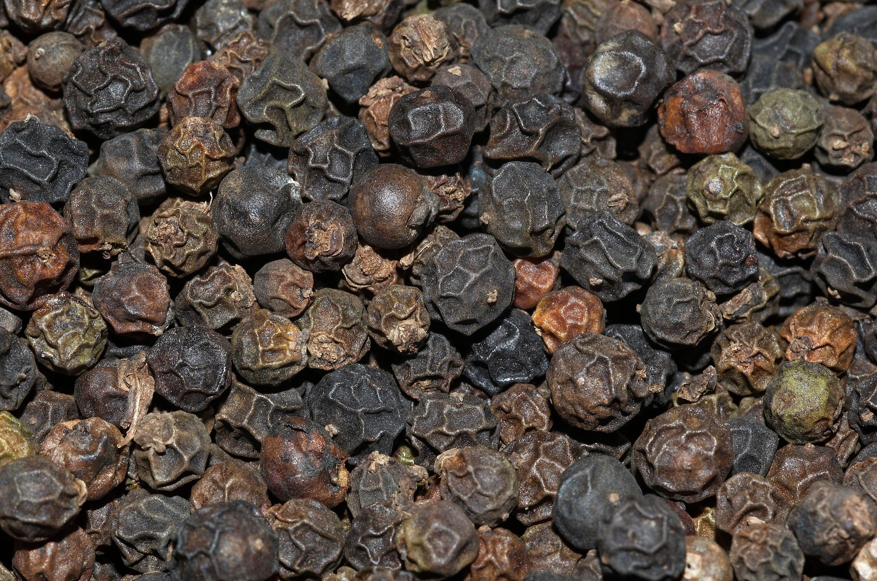 A close-up of black peppercorns.