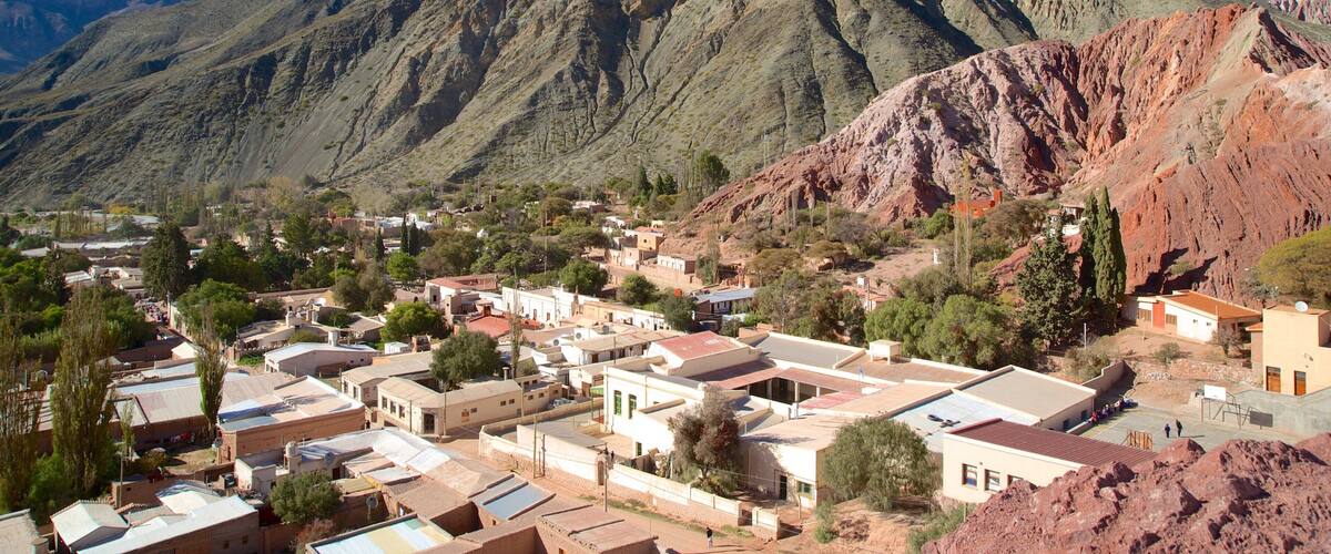 A town nestled against a mountainous backdrop with terraced houses and sparse vegetation.