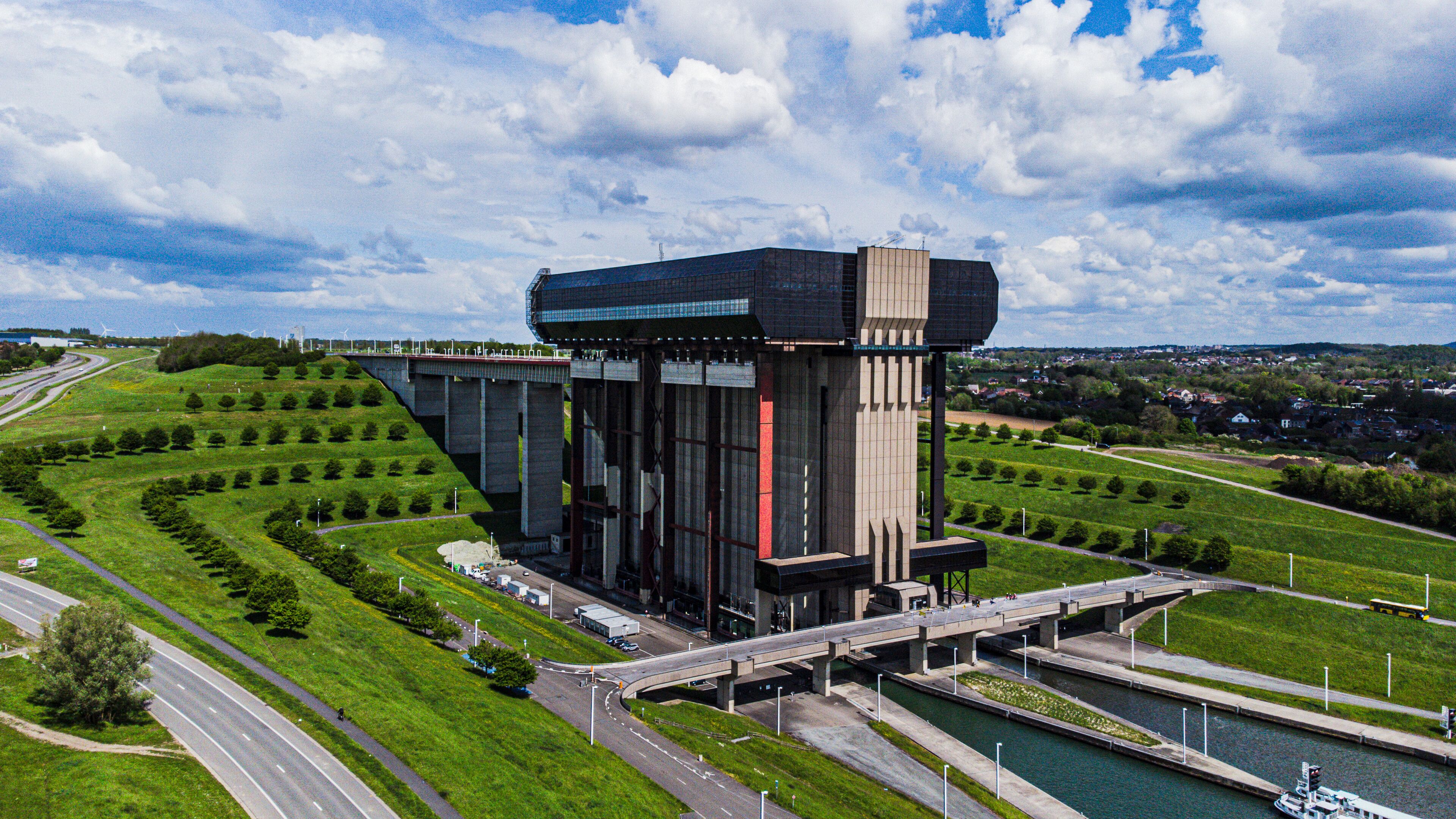 A modern building with a glass facade, a bridge, and a river.
