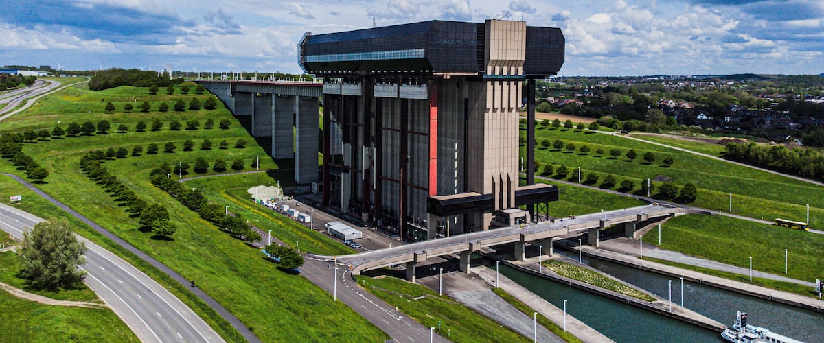 A modern building with a glass facade, a bridge, and a river.