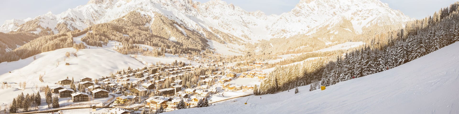 A snow-covered mountain village with ski slopes and lodge buildings.