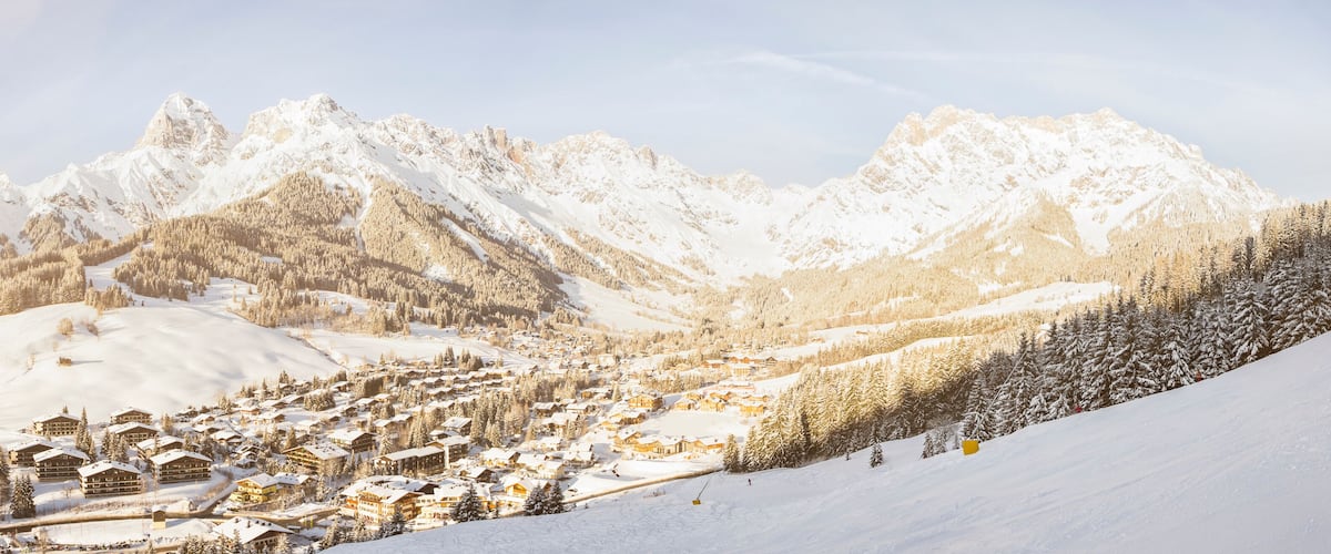 A snow-covered mountain village with ski slopes and lodge buildings.