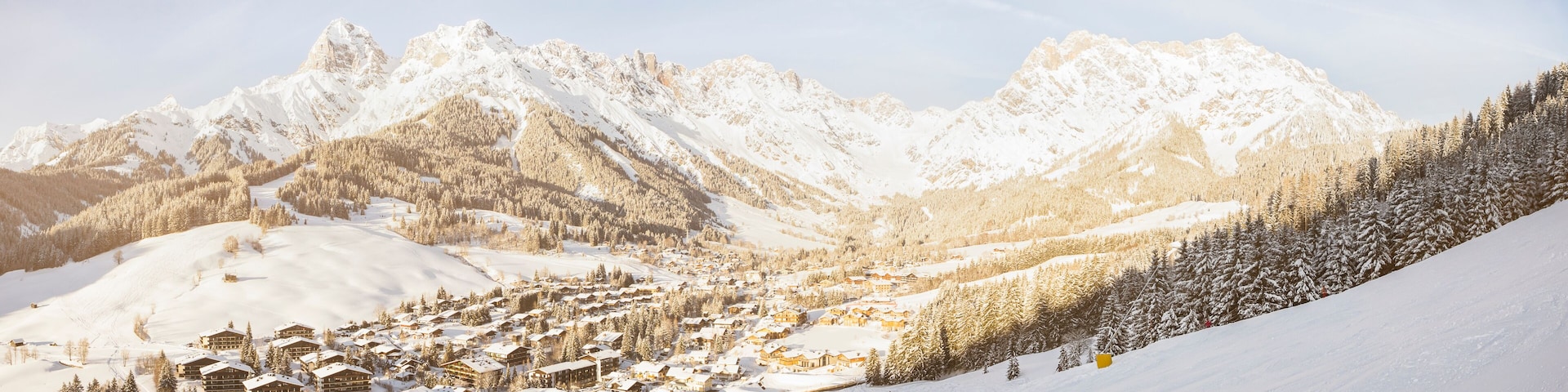 A snow-covered mountain village with ski slopes and lodge buildings.