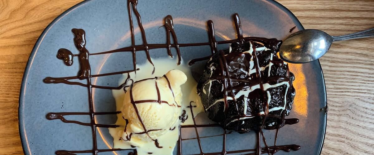 A dessert plate with chocolate and vanilla ice cream, drizzled with chocolate sauce.