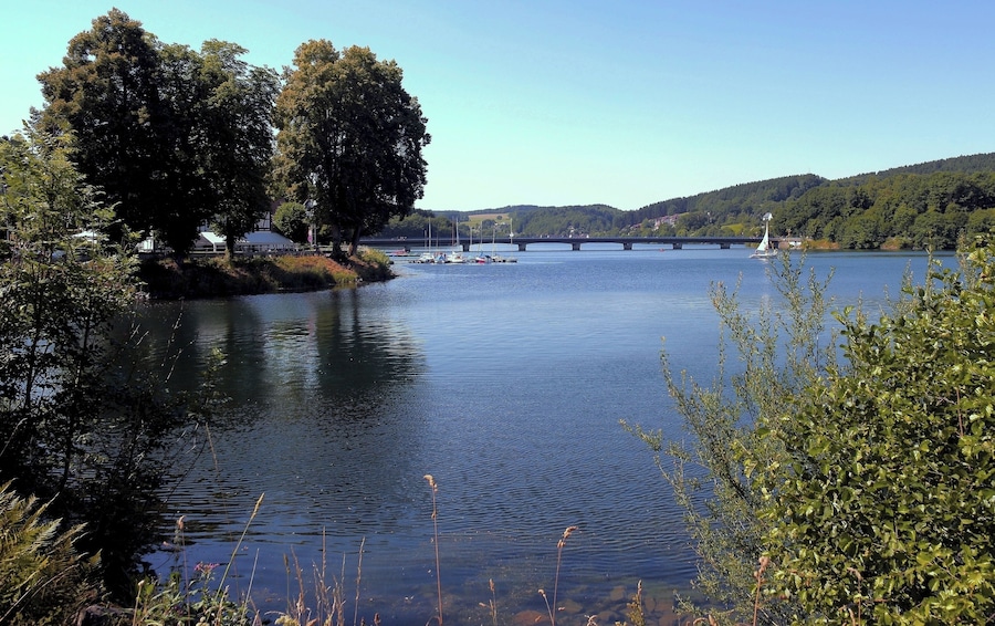Un río tranquilo con barcos, un puente y abundante vegetación.