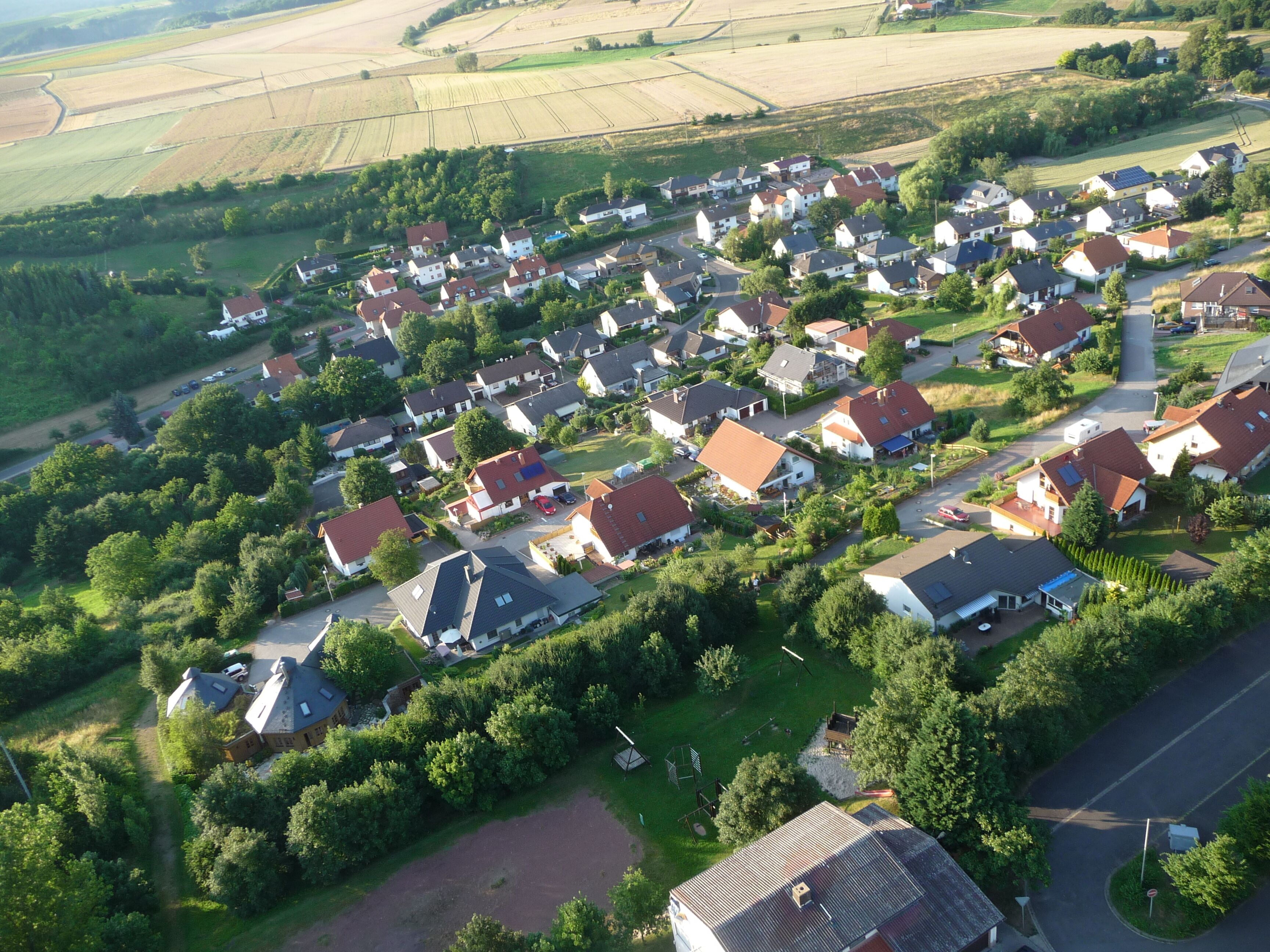 An aerial view of a residential area with houses, roads, and surrounding fields.