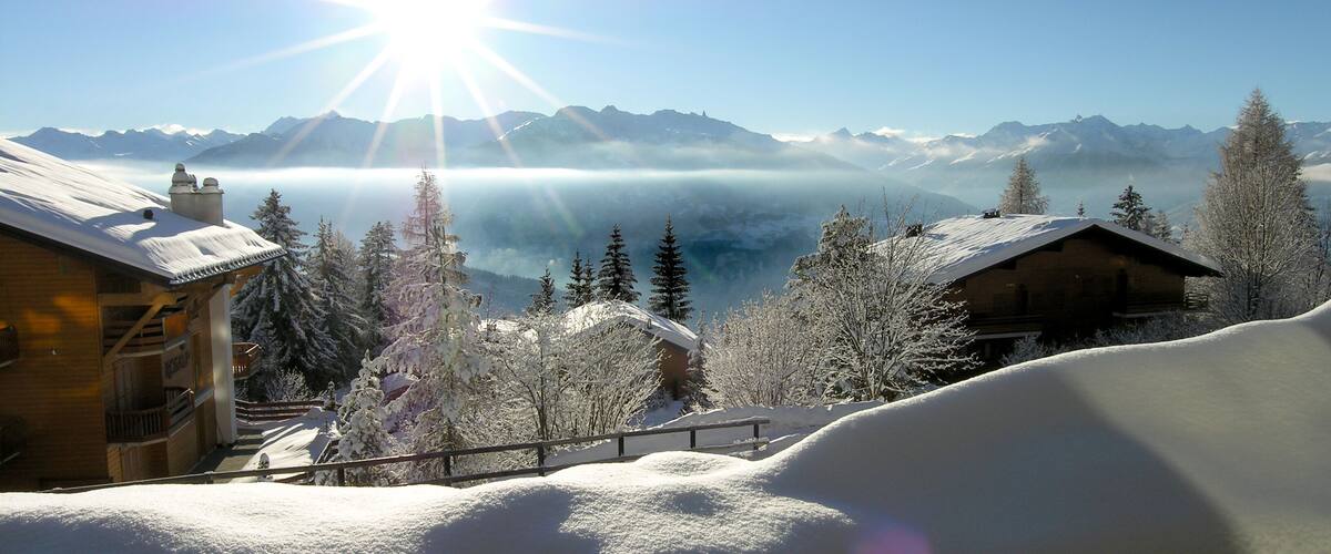 A snowy mountain landscape with cabins and a clear sky.