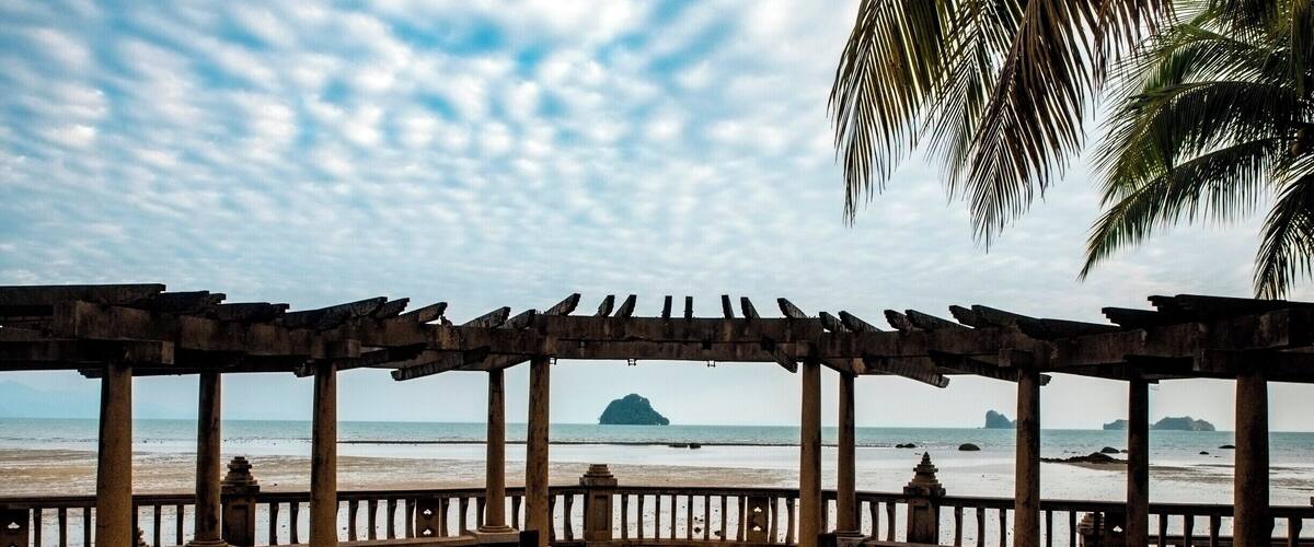 A wooden gazebo with columns overlooking the sea.