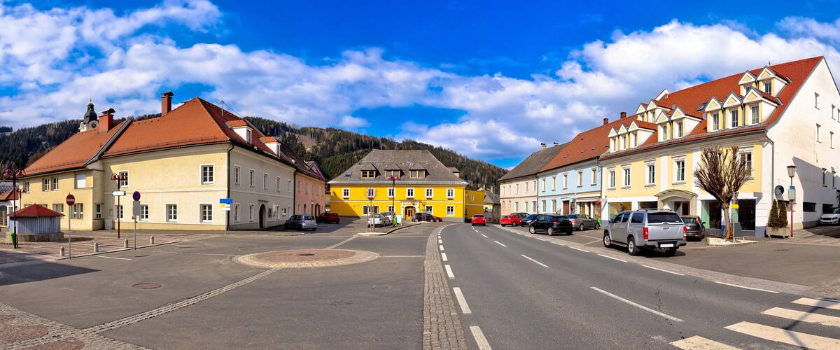 A town square with colorful buildings, a clear sky, and a mountain in the background.