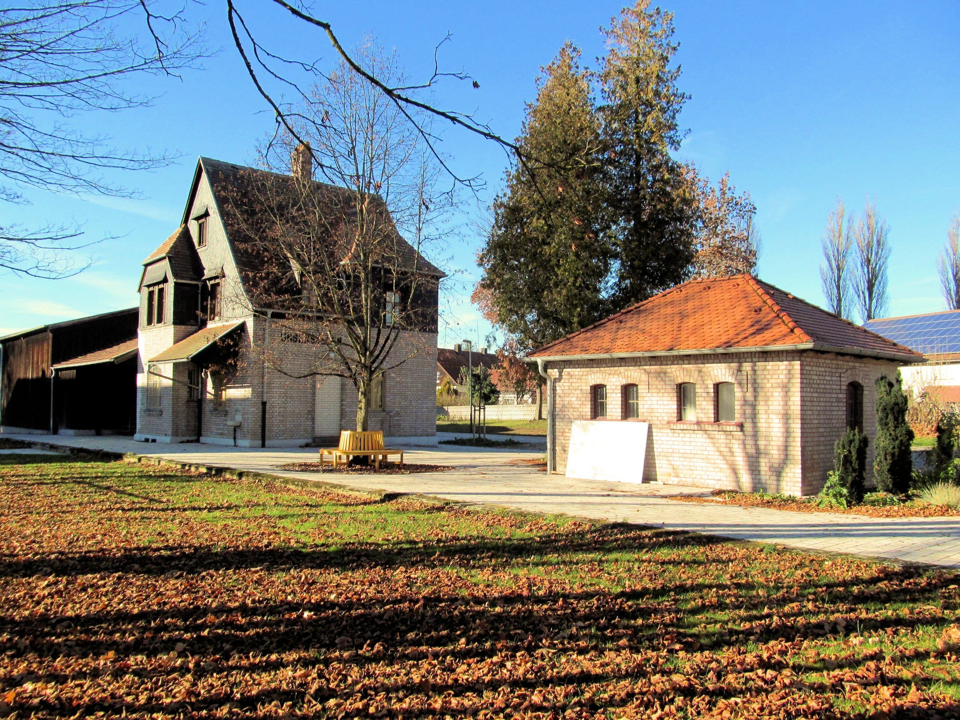 A historic building with a steep roof and a large tree in front.