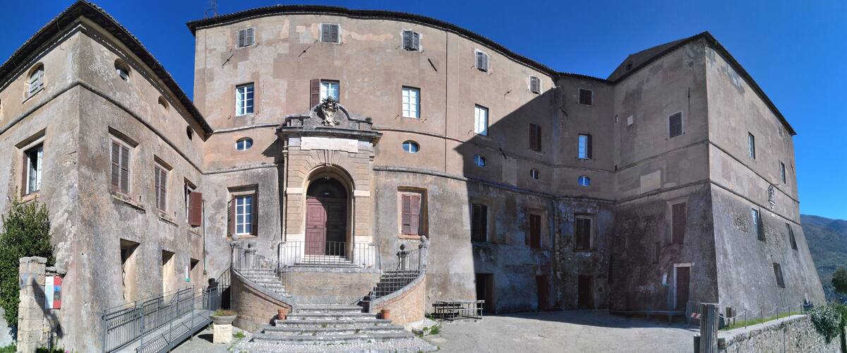 A historic building with a central archway, multiple windows, and a staircase leading to the entrance.