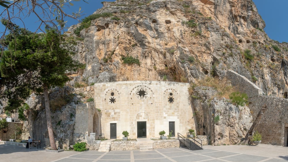 A historic building with star-shaped windows and a staircase leading up to it, set against a rocky cliff.