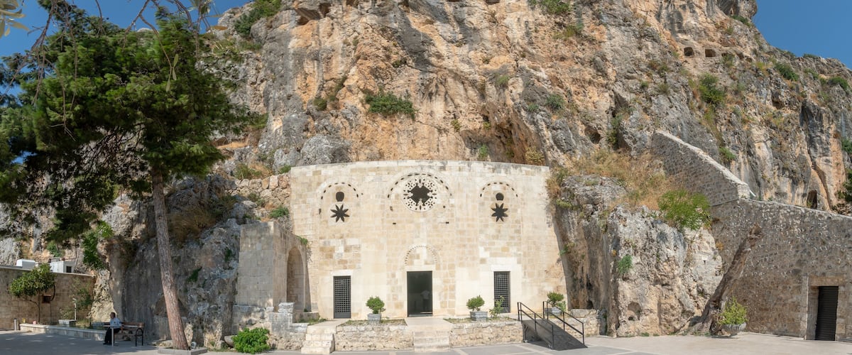 A historic building with star-shaped windows and a staircase leading up to it, set against a rocky cliff.