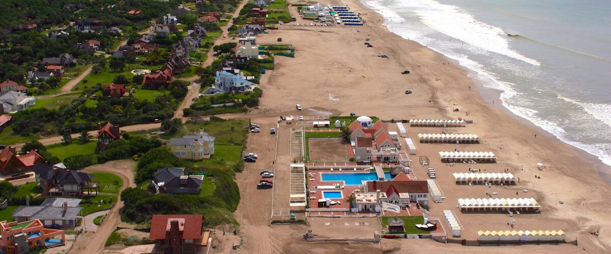 An aerial view of a coastal resort with a beach, swimming pool, and beach umbrellas.