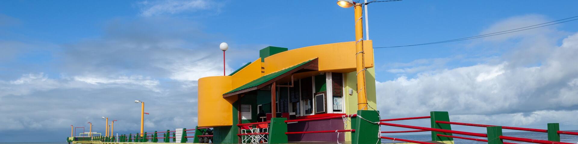 A colorful pier with a restaurant, a red railing, and a clear blue sky.