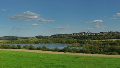 Schlammweiher Hahnwies der ehemaligen Grube Göttelborn, Blick von Steinertshaus Richtung Damm. Heute Teil der Landschaft der Industriekultur Nord (LIK.Nord), NaturschutzgroĂprojekt, Landschaftslabor Vogelzug und wilde Weiden. Im Hintergrund ist das FördergerĂŒst Schacht IV ("WeiĂer Riese") der ehemaligen Grube Göttelborn zu sehen (2017).