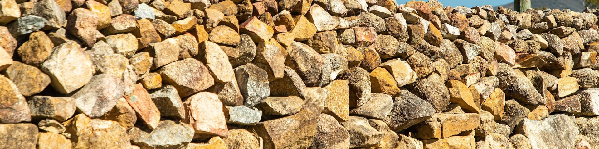 A sign for Tobin Wines with a stone wall in the foreground.