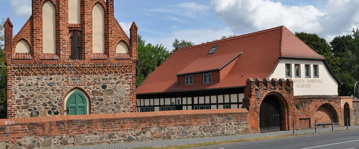 A church with a tall steeple and a hospital building with a red roof.