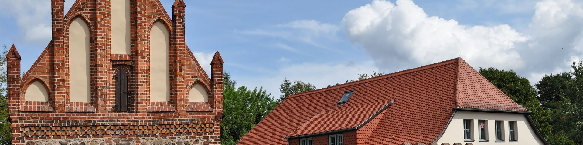 A church with a tall steeple and a hospital building with a red roof.