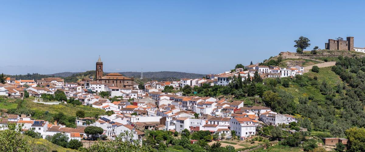 A hillside town with white buildings, a church, and a castle on a hill.