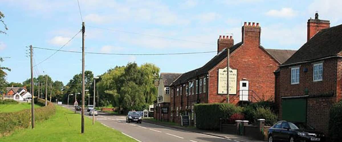 Entering Sibson from the South The road is the A444. Both Sibson pubs are visible here, The Millers in the centre of the picture, the Cock Inn is the white building on the far left.