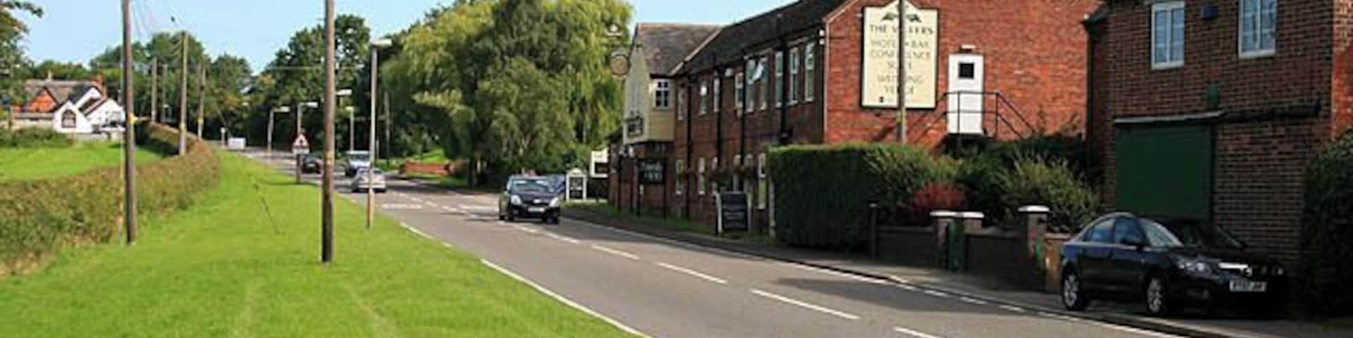 Entering Sibson from the South The road is the A444. Both Sibson pubs are visible here, The Millers in the centre of the picture, the Cock Inn is the white building on the far left.