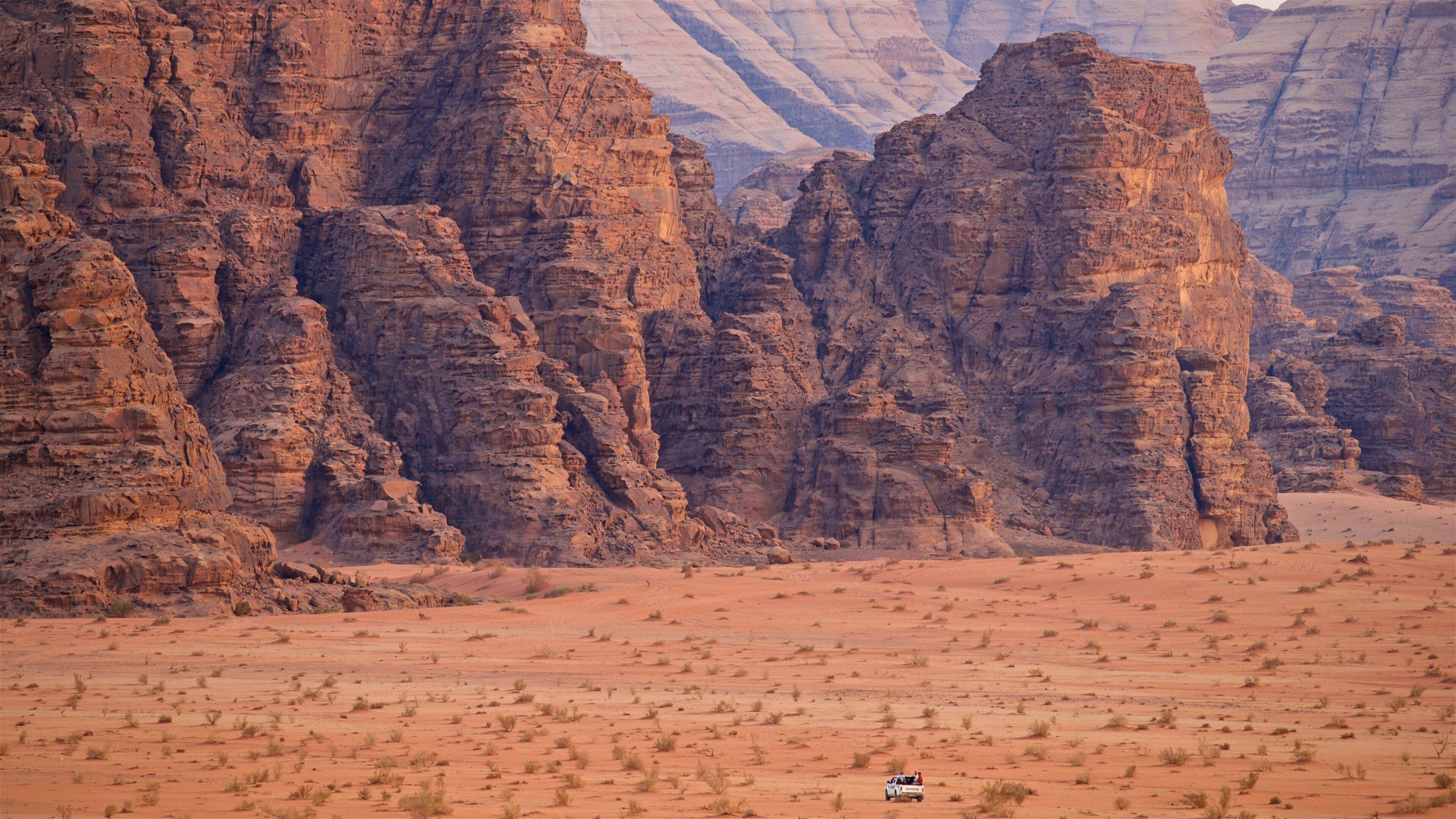A desert landscape with prominent sandstone rock formations and sparse vegetation.