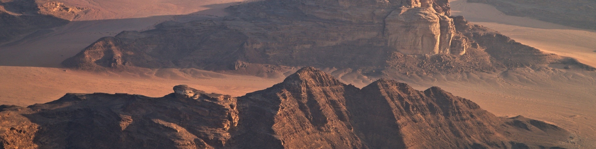 A desert landscape with prominent rocky formations and a distant waterfall.