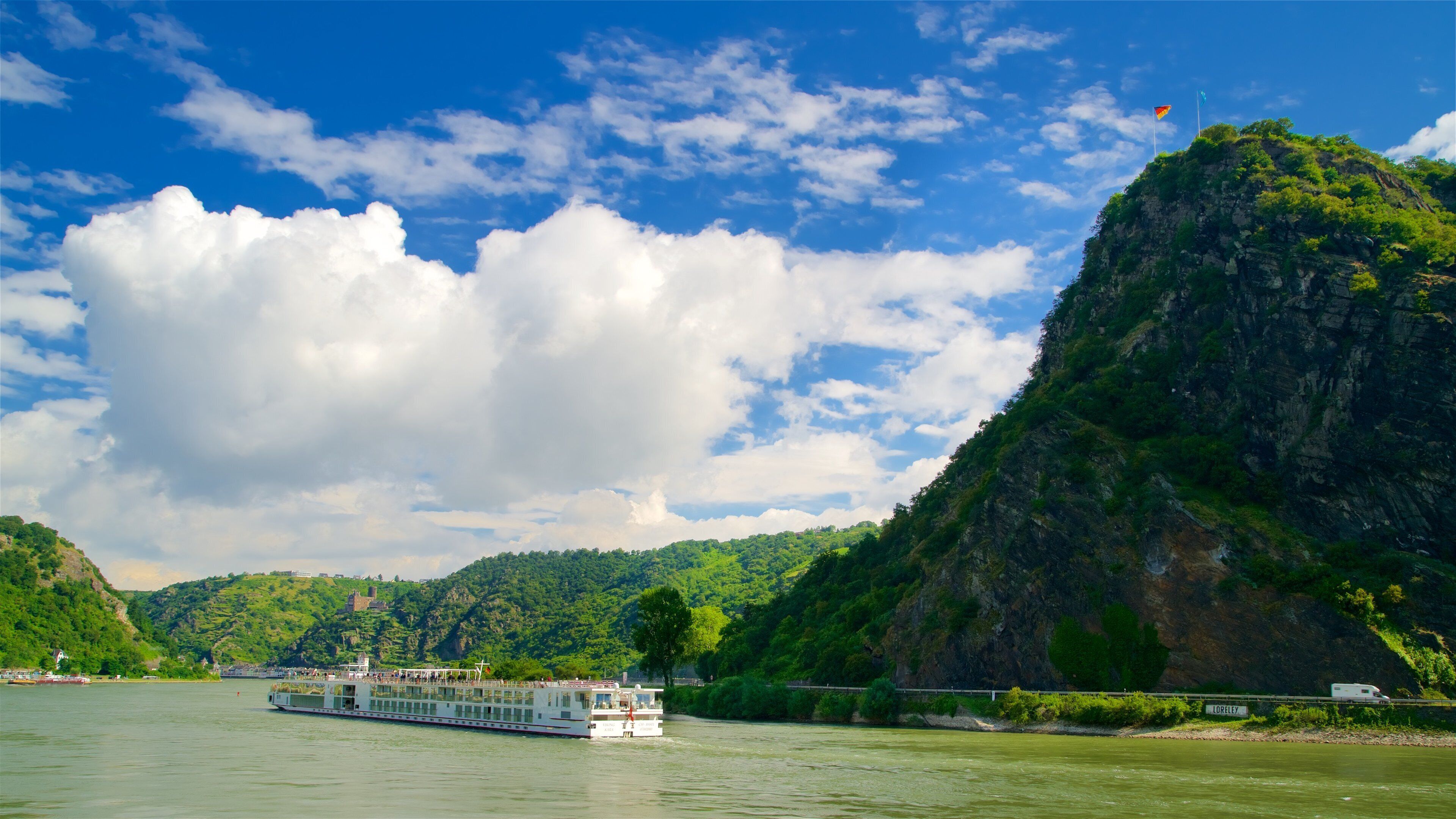 A river with a boat, a bridge, and a mountain.