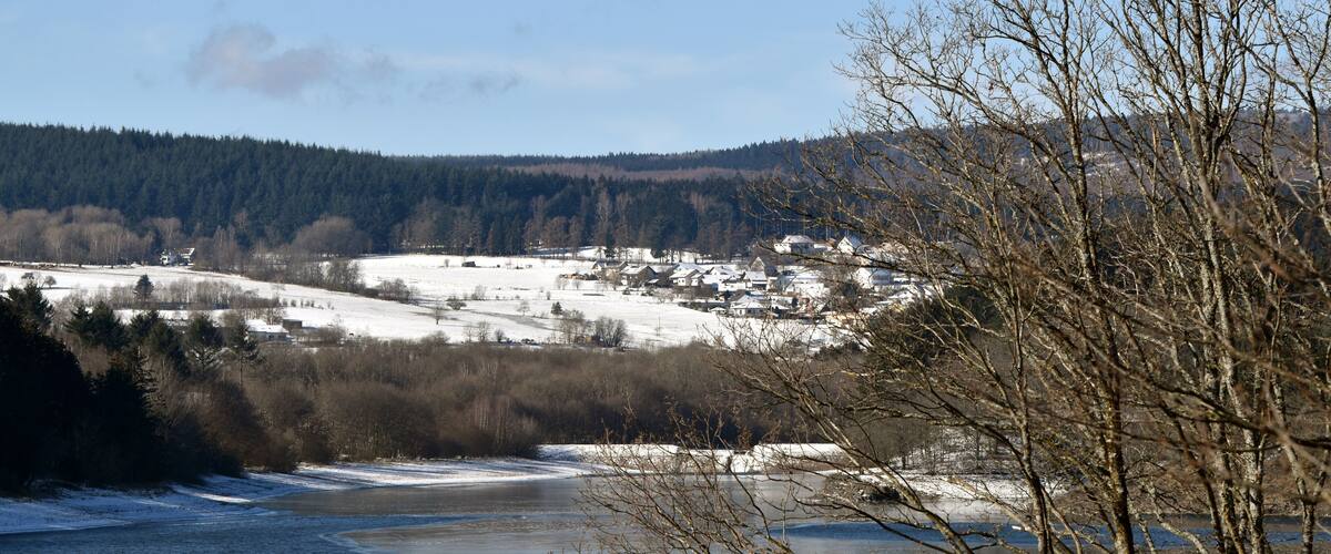 A frozen river with houses and trees in a snowy landscape.
