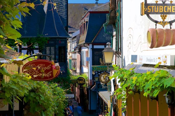 Eine schmale Straße mit Häusern, einem Schild für 'Drossauss No. 5' und einem Schild für 'Cafe Piasolo'.