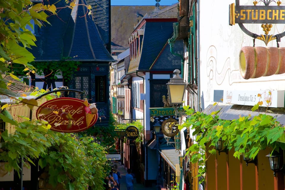 Uma rua estreita com edifícios, uma placa indicando 'Drossauss No. 5' e uma placa do 'Cafe Piasolo'.