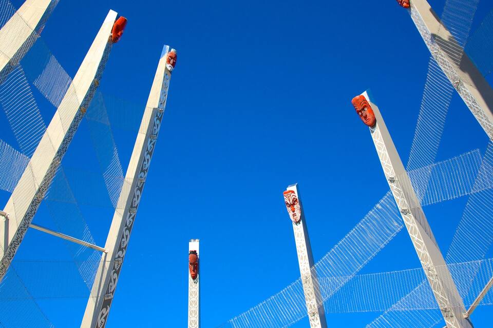 A series of tall poles with decorative elements against a clear blue sky.