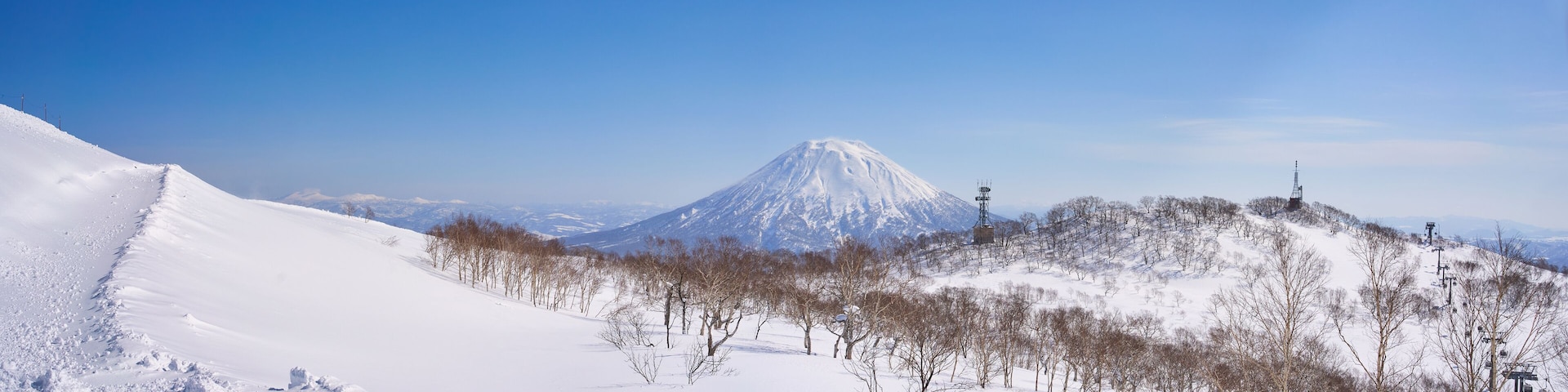 A snow-covered mountain with a ski lift and trees.