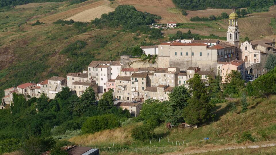 A hillside village with historic buildings and a church tower.