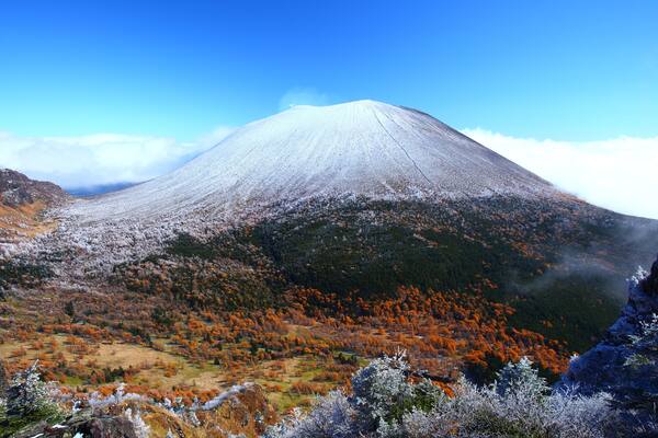 A snow-capped mountain with autumn foliage.