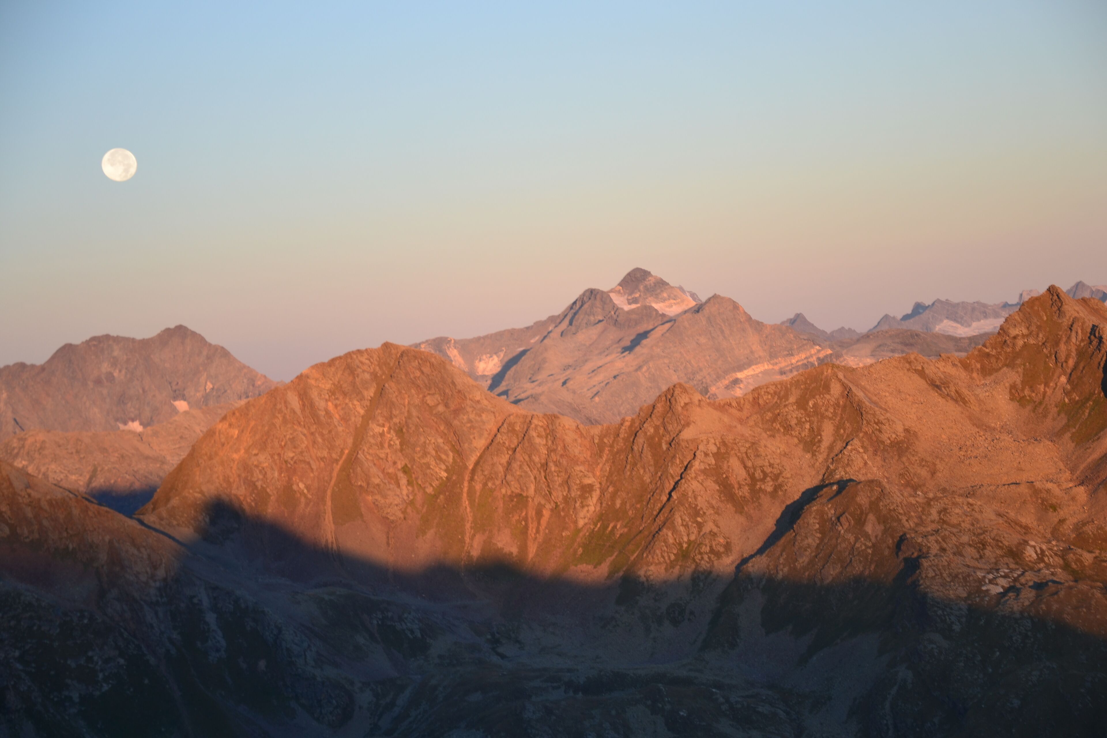A mountainous landscape with a prominent moon in the sky.