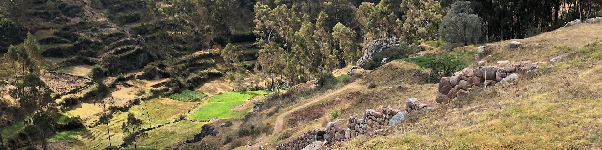 Campos escalonados, un muro de piedra y un paisaje montañoso.